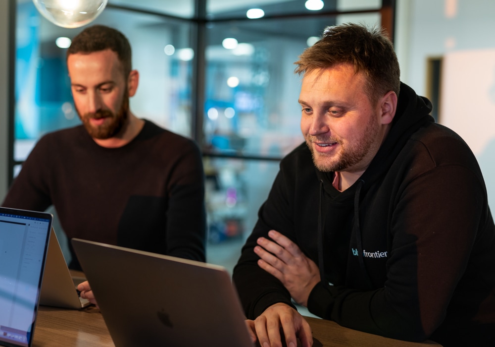 A designer smiles at their laptop whilst collaborating with a client