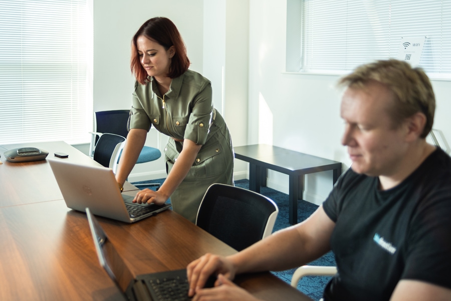 Two auditors look closely at their laptops in a small board room