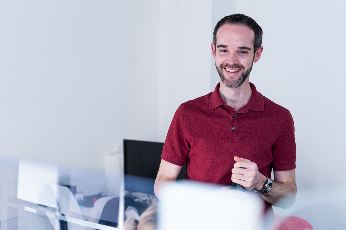 An IT technician smiles as they help a colleague