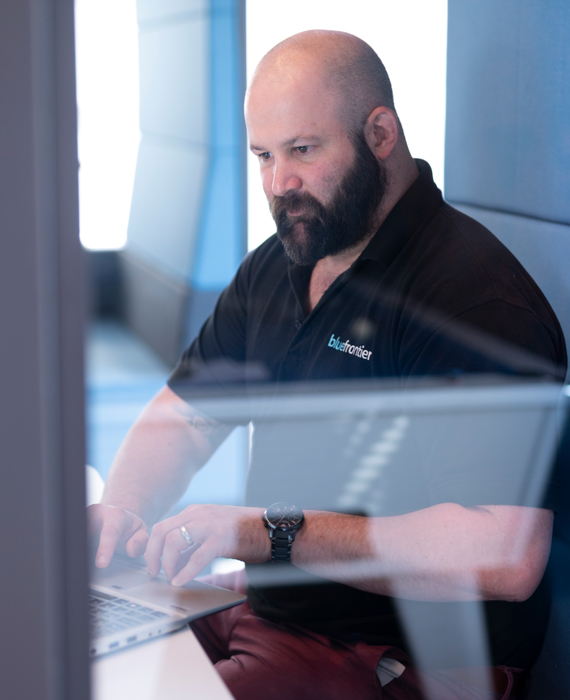 Brandon our Cyber Security Analyst working at a laptop in a meeting booth